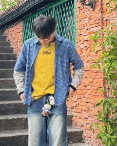 Maki Filipino singer wearing a grey long sleeves over a yellow shirt and checkered blue polo with kima charm