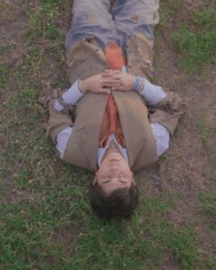 Maki Filipino singer wearing stressed suit over a polo with orange necktie